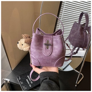 Detail view of purple matte bucket bag featuring metal buckle and cute bear charm