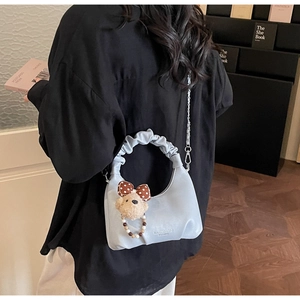 Detail of light blue crescent bag with pleated handle and cute bear charm pendant