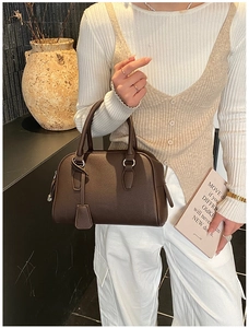 Close-up of a dark brown lychee leather bowling handbag with metallic zipper detail
