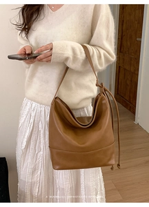 Brown leather large shoulder bag shown with minimalist drawstring detail on a model