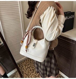 Détail du sac seau crème avec poignée en foulard de soie et breloque en bois