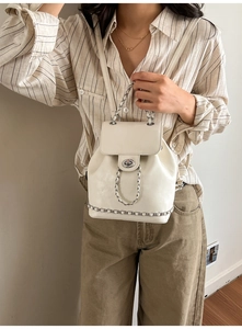 Detail of creamy white PU leather backpack featuring silver twist lock and chain strap