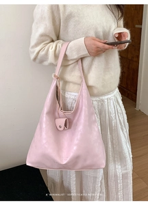 Close-up of minimalist pale pink leather tote bag with elegant metallic charm detail