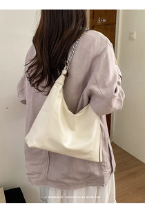 Detail showing the cream hobo bag with bold silver metal chain and fine faux leather texture