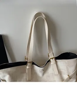 Detail of a beige tote bag showing high-quality leather straps and golden metal buckle