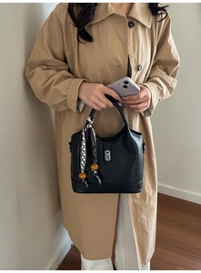 Détail du sac seau en cuir noir avec fermoir argenté et foulard en soie décoratif