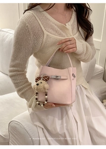 Detail of pink retro bucket bag with metallic buckle and cute polka dot bear pendant