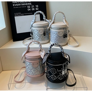 Detail of color-block bucket bags featuring geometric embossed patterns and scarf handles