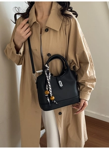 Détail du sac seau en cuir noir avec foulard géométrique et perles décoratives en bois