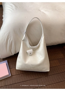 Detail of creamy white leather tote bag with small matching pouch and brand lettering