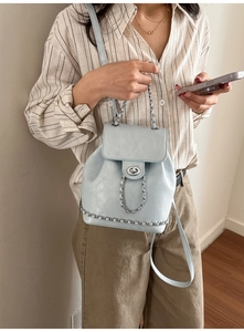 Detail of light blue faux leather backpack with silver chain accents and twist lock