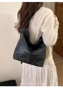 Minimalist black leather tote bag shown on a model's shoulder for casual daily use