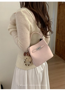 Detail of pink leather bucket bag with silver turn-lock and cute teddy bear charm accessory