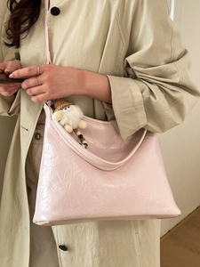 Borsa hobo rosa plissettata con ciondolo di peluche, indossata con un trench kaki