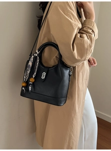 Détail d'un sac seau noir en cuir avec foulard en soie et fermoir rotatif argenté