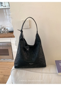 Detail of minimalist black hobo bag with knotted strap and small detachable coin purse
