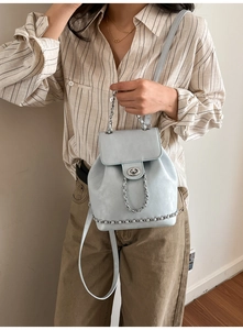 Detail of light blue mini backpack with silver metal twist lock and chain strap accents