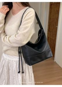 Side view of a large black leather hobo bag with drawstring detail for women