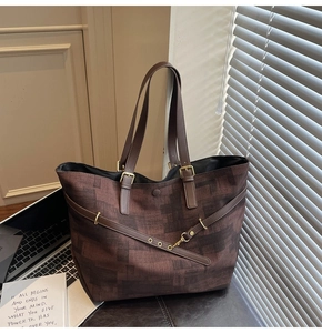 Detail view of large tote bag with dark brown checkered pattern and leather straps