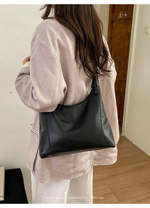 Close-up of minimalist black large capacity hobo shoulder bag with smooth faux leather texture