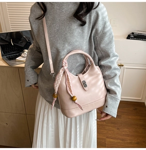 Détail du sac seau en cuir rose avec foulard à carreaux, perles en bois et fermoir en métal argenté