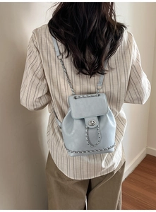 Rear view of a light blue mini backpack with silver chain trim and thin shoulder straps