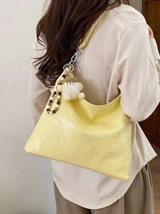 Borsa sottobraccio giallo chiaro in pelle stropicciata con charm in peluche sulla modella