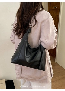 Detail of black PU leather shoulder bag with bold silver metal chain strap on model