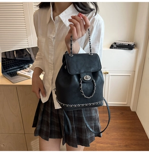 Detail of black bucket backpack featuring silver chain strap and twist lock closure