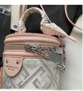 Detailed macro view of the smooth metal zipper and leather strap on the pink bucket bag