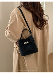 Detail of black leather bucket bag with silver hardware and cute bear charm accessory