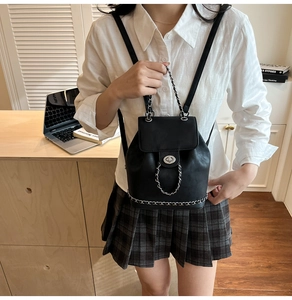 Close-up of black leather backpack with metal chain decor and twist lock closure