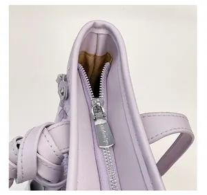 Close-up of a silver metal zipper and stitching on a light purple leather tote bag