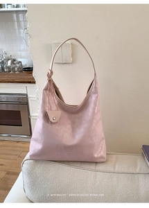 Pink leather hobo bag detailed with matching small button pouch on light sofa