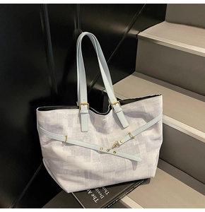 Detail view of the large tote bag showing abstract blue texture and golden metal buckle