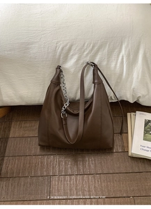 Close-up of brown leather shoulder bag with silver chain detail and retro minimalist style