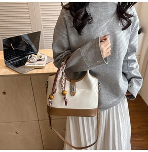 Détail du sac seau crème et marron avec foulard décoratif en soie et pendentif en bois