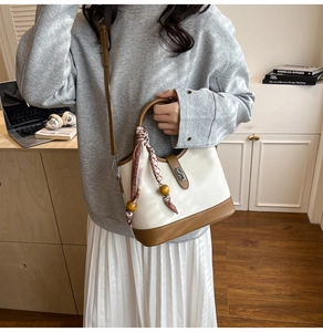 Détail d'un sac seau bicolore avec poignée en foulard et fermoir métallique argenté