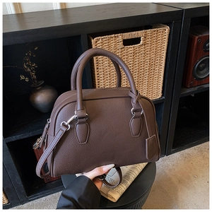 Detail of dark brown lychee leather handbag with silver zippers and removable strap