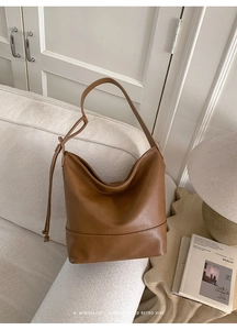 Macro detail of brown vintage leather hobo bag with drawstring on white sofa