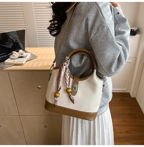 Détail d'un sac seau bicolore avec anse en foulard et pendentif en perles de bois