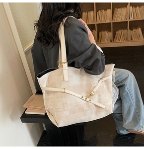 Detail view of large canvas tote bag with adjustable leather straps and metal buckle