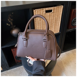 Detail of dark brown lychee leather Boston bag featuring silver metal zippers and handles