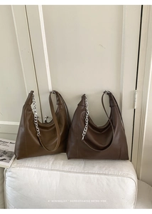 Detail of retro hobo bags in brown leather with decorative silver chain and strap