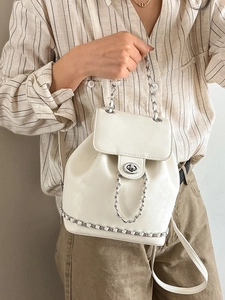 White PU leather backpack with silver chain trim and turn-lock closure on model