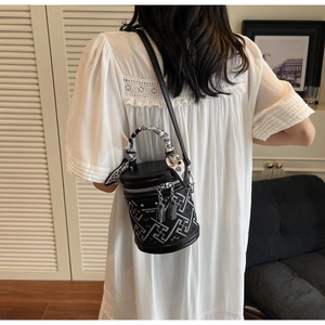 Detail showing cylindrical bucket bag with geometric patterns and floral silk scarf handle