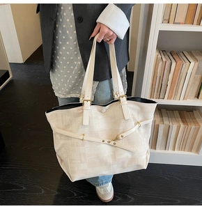 Detailed close-up of beige tote bag showing gold hardware and geometric texture