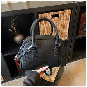 Detail of black lychee grain leather bowling bag with dual handles and shoulder strap