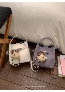 Detail showing white and purple bucket bags with bear pendants and metal buckles