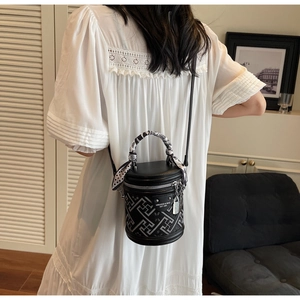 Close-up of black bucket bag with geometric patterns and scarf-wrapped handle detail